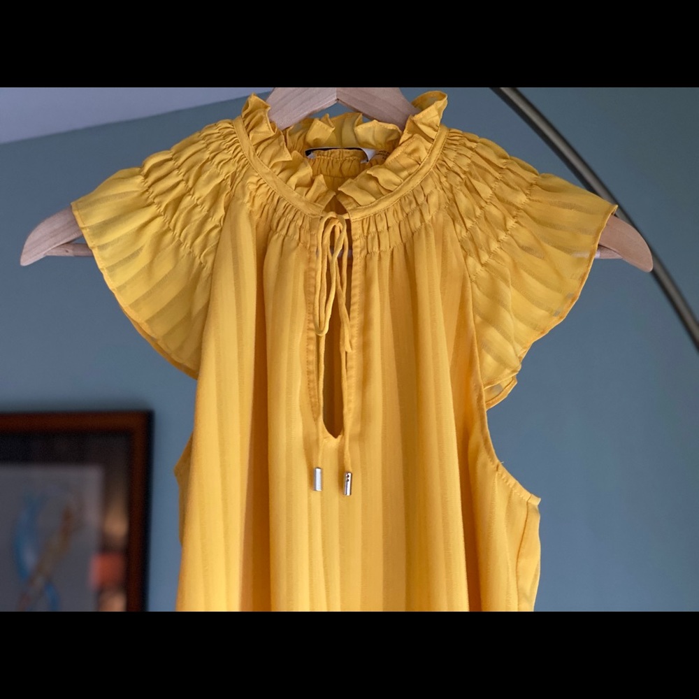 Yellow pleated blouse with tie string collar.